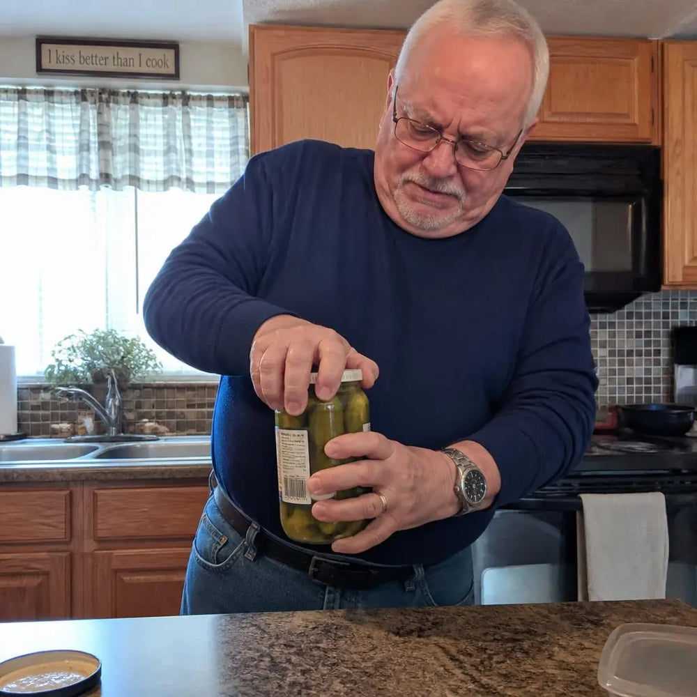 Older man struggling to open a glass jar, a sign of declining grip strength