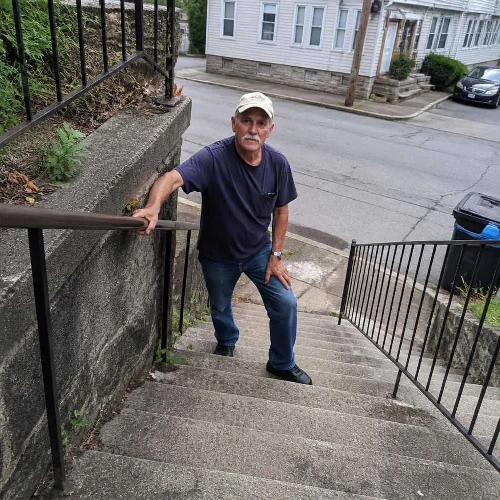 Older man pausing on a staircase holding the handrail